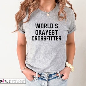 May include: A gray t-shirt with black text that reads "WORLD'S OKAYEST CROSSFITTER".