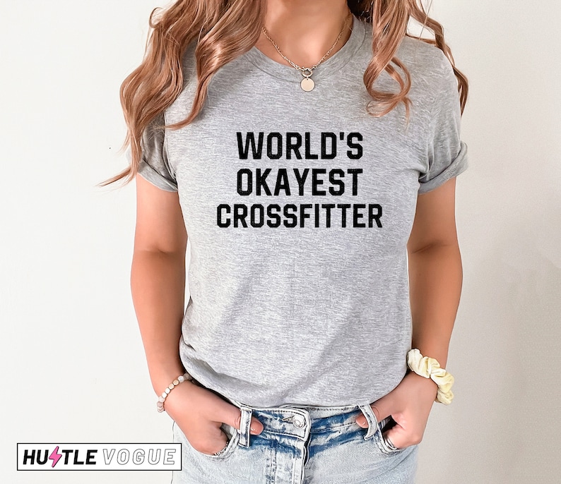 May include: A gray t-shirt with black text that reads "WORLD'S OKAYEST CROSSFITTER".