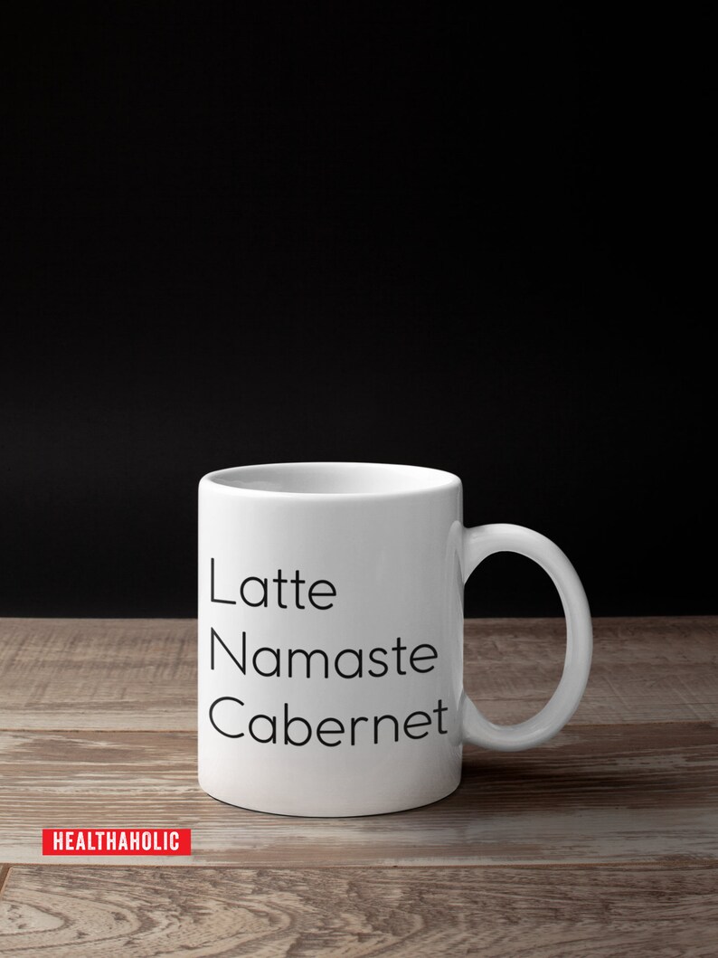 Pu&ograve; includere: Tazza in ceramica bianca con testo nero che recita "Latte, Namaste, Cabernet".