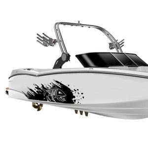 May include: A white boat with a black and white graphic of a fish on the side. The boat has a tower with a wakeboard rack.