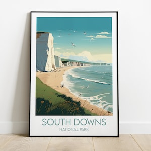 May include: A vintage-style travel poster featuring a scenic view of the South Downs National Park in England. The poster depicts white cliffs along a sandy beach with blue ocean waves and a bright blue sky with white clouds. The text "South Downs National Park" is printed in green and black at the bottom of the poster.
