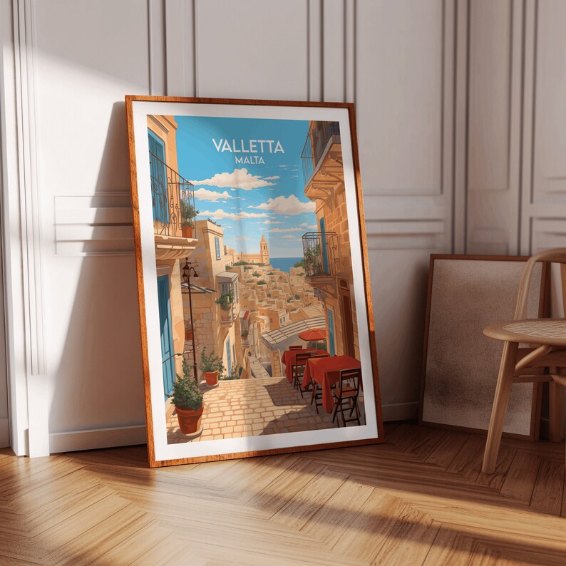 May include: A vintage travel poster featuring a colorful illustration of a narrow street in Valletta, Malta. The street is lined with buildings and has a view of the sea in the distance. There are tables and chairs set up outside a cafe, with red tablecloths and umbrellas.