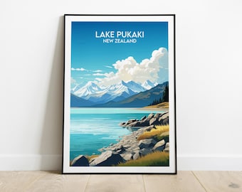May include: A framed poster with a scenic illustration of Lake Pukaki in New Zealand. The poster features a blue lake with snow-capped mountains in the background and a rocky shoreline in the foreground. The text "LAKE PUKAKI NEW ZEALAND" is printed at the top of the poster.