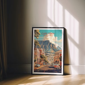 May include: A vintage travel poster featuring a colorful illustration of Cape Town, South Africa. The poster depicts a street scene with buildings, palm trees, and a mountain in the background. The text "CAPE TOWN SOUTH AFRICA" is displayed at the top of the poster.