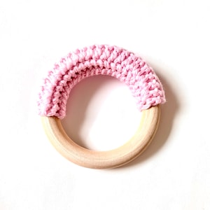 May include: A pink crocheted ring attached to a wooden teething ring.