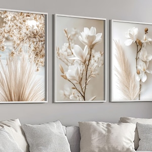 Può includere: Tre stampe artistiche botaniche incorniciate. Le stampe presentano primi piani di fiori e piante in tonalità neutre. La prima stampa mostra un gruppo di fiori beige e erba alta e piumosa. La seconda stampa mostra fiori di magnolia bianca. La terza stampa mostra fiori bianchi.