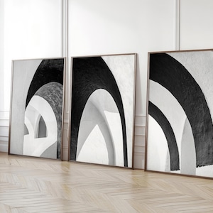 Könnte beinhalten: Drei Schwarzweiß-Abstrakte Kunstdrucke mit einem geometrischen Design aus Bögen. Die Drucke sind in einem dünnen schwarzen Rahmen gerahmt und hängen an einer weißen Wand.