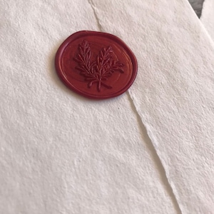 May include: A red wax seal with a leafy design.