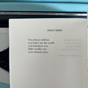 Puede incluir: P&aacute;gina de libro con el texto "You always told me you'd give me the world as if somehow you didn't realise you were already mine." de HOLLY KERR. Una m&aacute;quina de escribir azul vintage en el fondo, creando un ambiente nost&aacute;lgico.