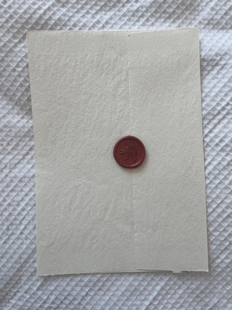 May include: A white envelope with a red wax seal featuring a floral design.