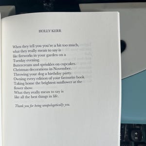 Puede incluir: Un libro abierto con texto de Holly Kerr, sobre una m&aacute;quina de escribir azul. El texto incluye frases como "fuegos artificiales en tu jard&iacute;n" y "sin disculpas".