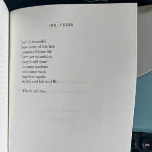 Puede incluir: Una p&aacute;gina de libro abierta muestra un poema de Holly Kerr. El poema comienza con "Isn't it beautiful" y trata sobre las estaciones de la vida y el tiempo. El texto negro est&aacute; en una p&aacute;gina blanca, con el nombre del autor en la parte superior.