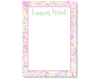 May include: A rectangular notepad featuring a white centre bordered by a pink line and a floral pattern of pink, yellow, and purple flowers with green leaves. The name Lauren Wood is printed in a light green script font at the top centre.