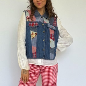 Op de afbeelding: Een spijkerbroekvest met patchworkdetails, gecombineerd met een witte blouse en een rood-witte geruite flared broek. Een rode baret maakt de outfit compleet en creëert een vintage, retro esthetiek. De ensemble is een mix van texturen en patronen.