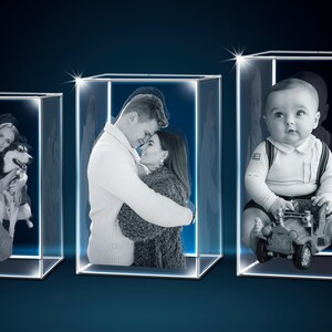 Puede incluir: Tres cajas de exhibici&oacute;n de vidrio iluminadas que muestran grabados fotogr&aacute;ficos personalizados. Las im&aacute;genes presentan a una mujer con un perro, una pareja abraz&aacute;ndose y un beb&eacute; con un coche de juguete. Dise&ntilde;o moderno y minimalista.