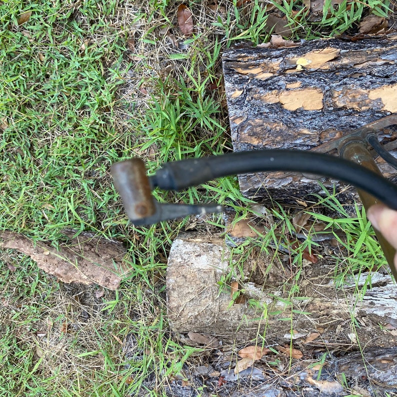 Puede incluir: Primer plano de una bomba de bicicleta negra y plateada con una boquilla de metal. La bomba est&aacute; sobre una superficie de madera.
