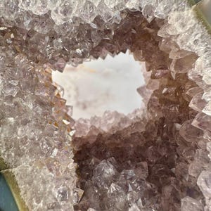 May include: A large amethyst geode with a natural opening revealing a cluster of purple crystals. The geode has a smooth, gray exterior.
