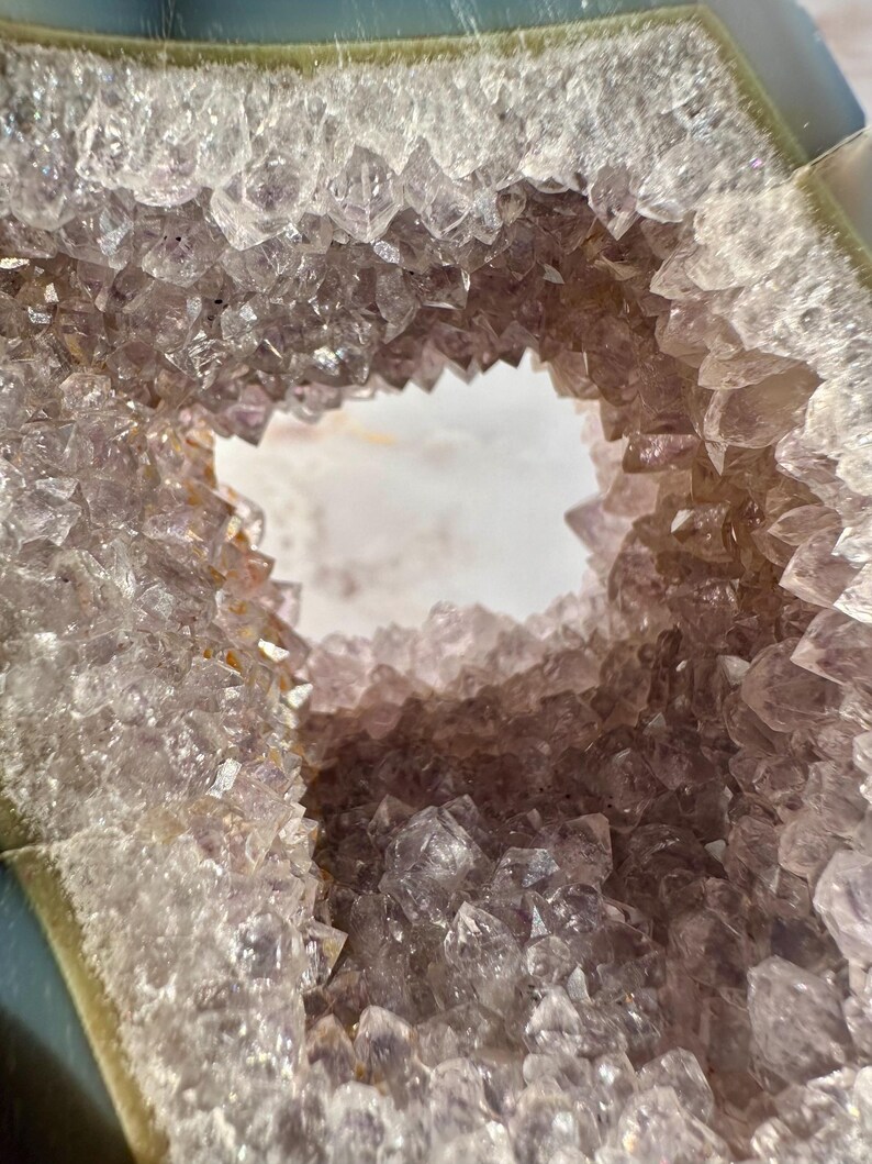 May include: A large amethyst geode with a natural opening revealing a cluster of purple crystals. The geode has a smooth, gray exterior.