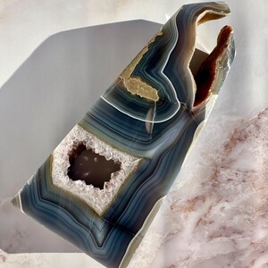 May include: A large, blue and white agate geode with a natural opening. The geode has a unique, organic shape and is perfect for display.