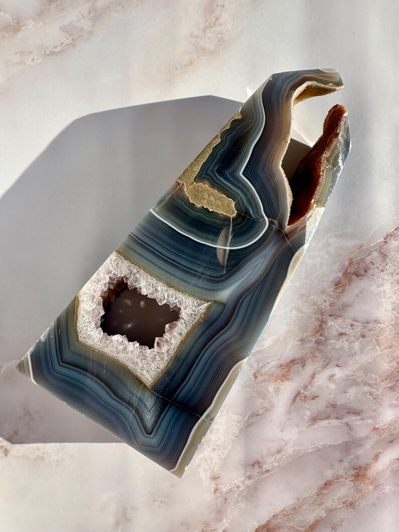 May include: A large, blue and white agate geode with a natural opening. The geode has a unique, organic shape and is perfect for display.