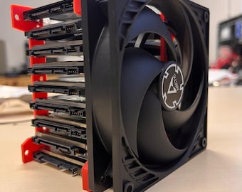May include: A black hard drive enclosure with a red frame and a black fan with a white Arctic logo. The enclosure is stacked with multiple hard drives.