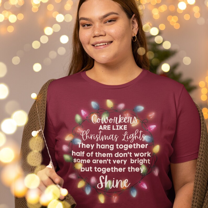 Puede incluir: Una camiseta color burdeos con un dise&ntilde;o de luces de Navidad y el texto "Coworkers are like Christmas Lights. They hang together, half of them don't work, some aren't very bright, but together they shine."