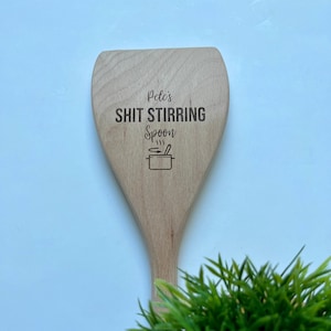 Peut inclure: Une cuillère en bois avec le texte "Pete's Shit Stirring Spoon" et une petite illustration d'une casserole avec de la vapeur qui s'en échappe.