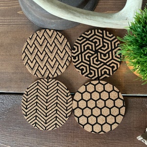 May include: Set of four cork coasters featuring black and white geometric patterns. The designs include a chevron, a honeycomb, a geometric grid, and a repeating hexagon pattern.