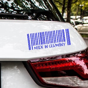Peut inclure: Une voiture blanche avec un autocollant de code-barres bleu qui dit "MADE IN GERMANY" à l'arrière.