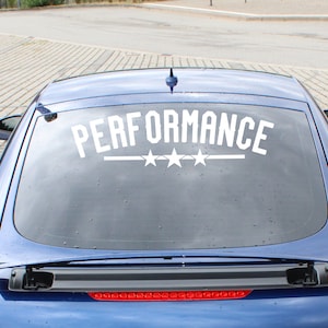 以下が含まれることがあります： リアウィンドウに「PERFORMANCE」と3つの星が書かれた白いビニールステッカーが貼られた青い車