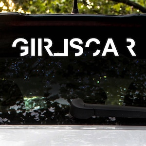 May include: A black car with a white vinyl decal on the rear window that reads "GIRLSCAR".