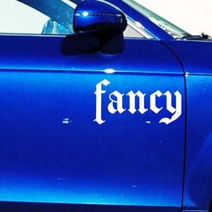 Può includere: Un'auto blu con un adesivo bianco "fancy" sul lato.