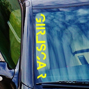 May include: A yellow vinyl decal with the word "CARS" written vertically on a car windshield.
