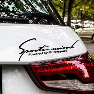 May include: A white car with a black "Sport mind Powered by Motorsport" decal on the back.