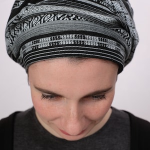 May include: A person wearing a black and white patterned head covering. The head covering is made of a soft, woven fabric. The person is looking down.