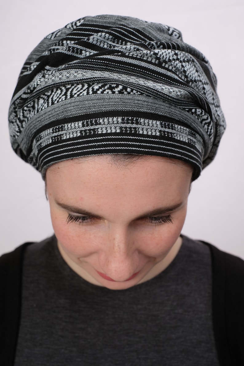 May include: A person wearing a black and white patterned head covering. The head covering is made of a soft, woven fabric. The person is looking down.