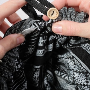 May include: Black and white patterned fabric with a wooden button that says "Handmade with love" and a black elastic band.