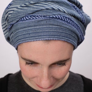 May include: A person wearing a blue and white striped head covering. The head covering is made of a soft, woven fabric.