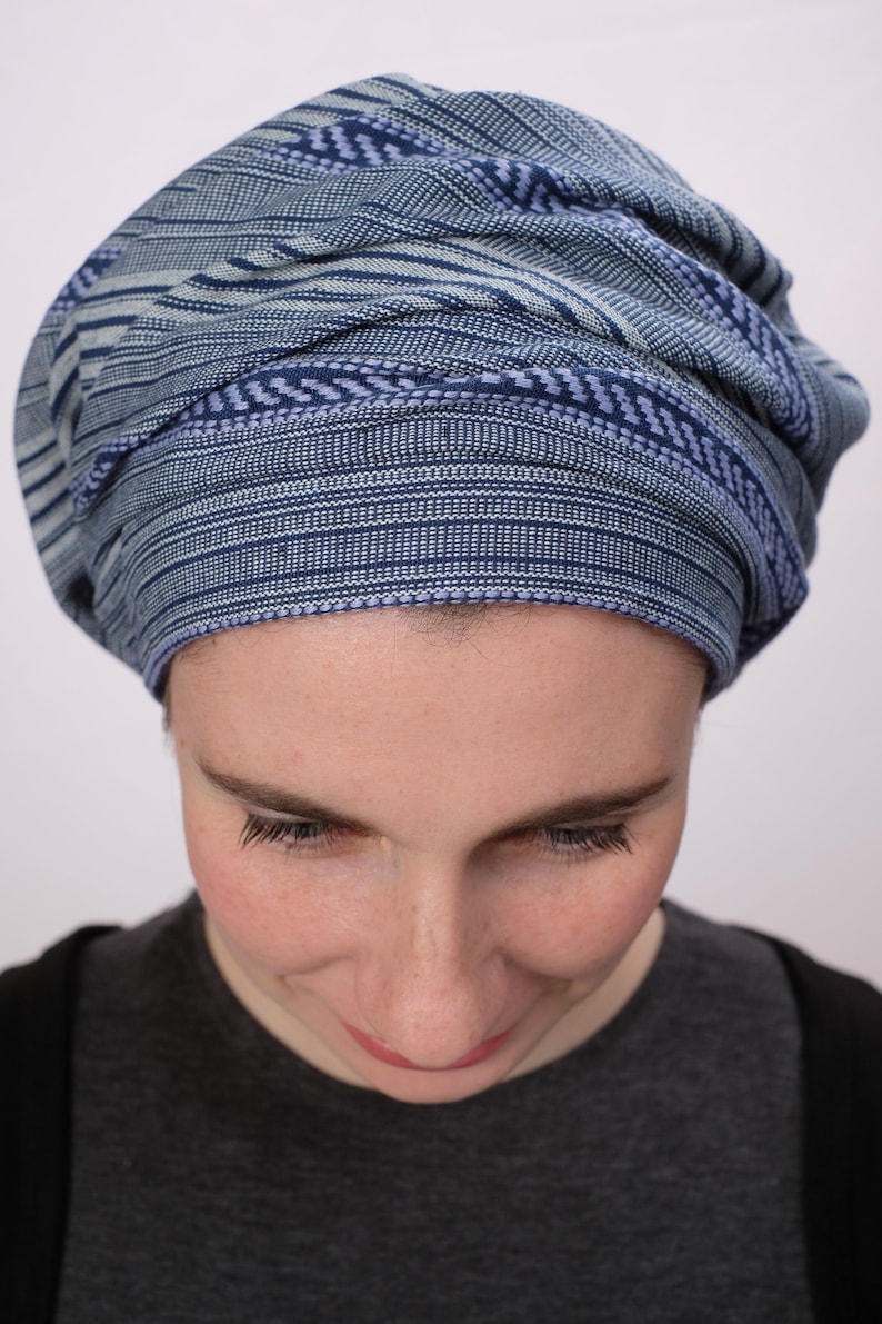 May include: A person wearing a blue and white striped head covering. The head covering is made of a soft, woven fabric.