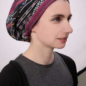 May include: A woman wearing a black and pink patterned head covering with a black and grey shirt.
