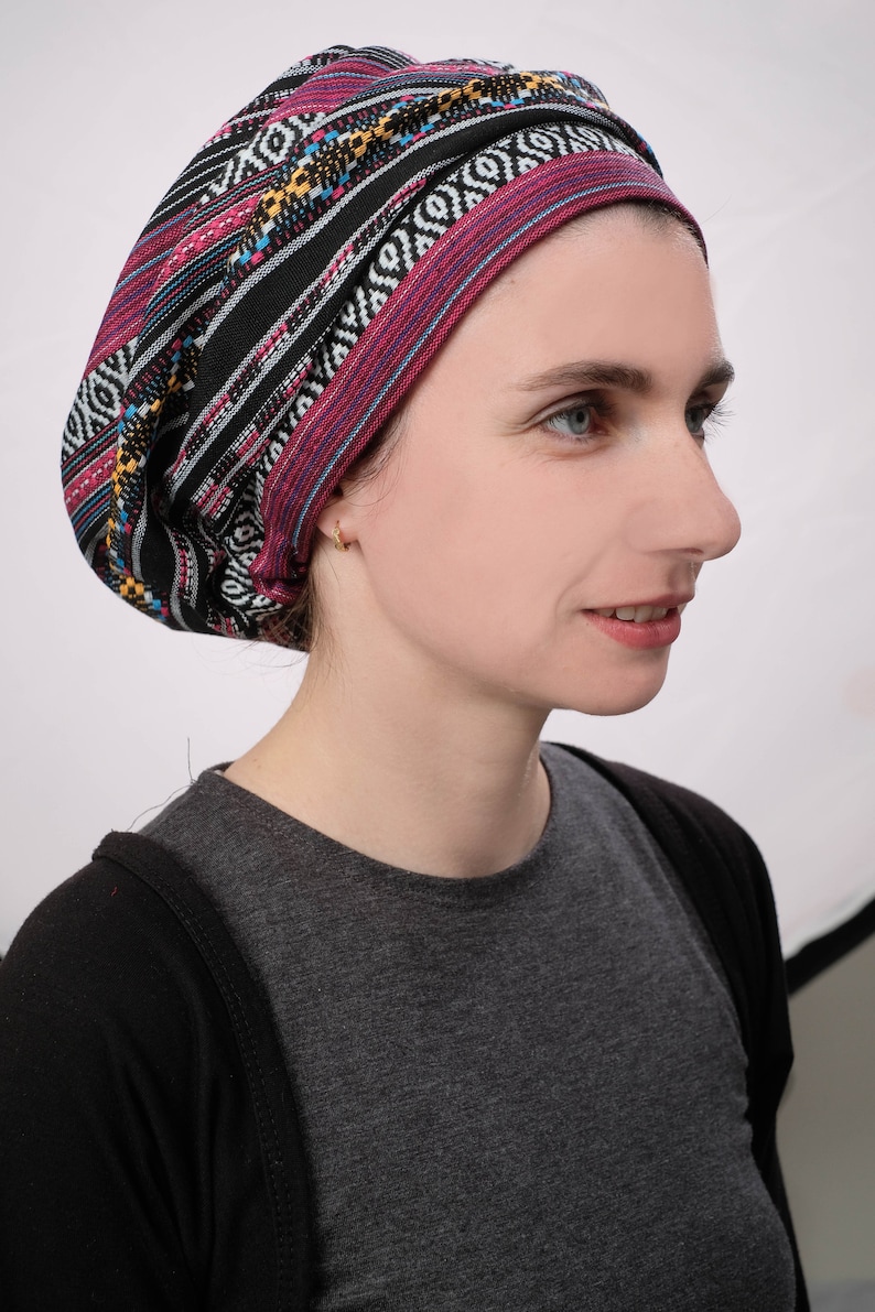May include: A woman wearing a black and pink patterned head covering with a black and grey shirt.