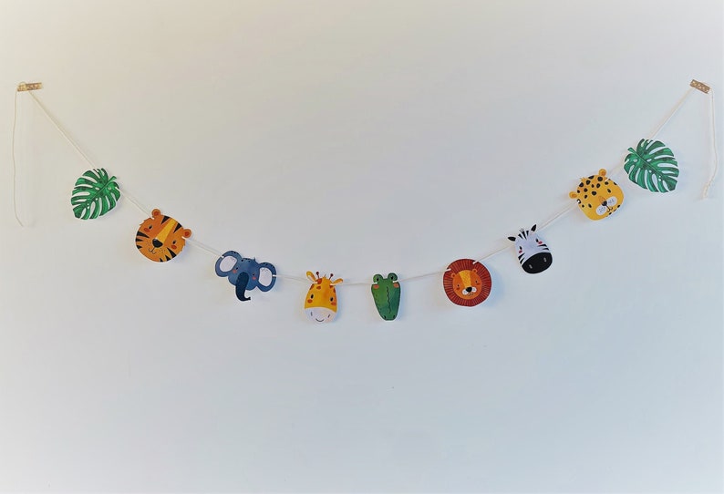 May include: A colorful garland with animal faces, including a tiger, elephant, giraffe, frog, lion, zebra, and leopard, with green leaves on either end.