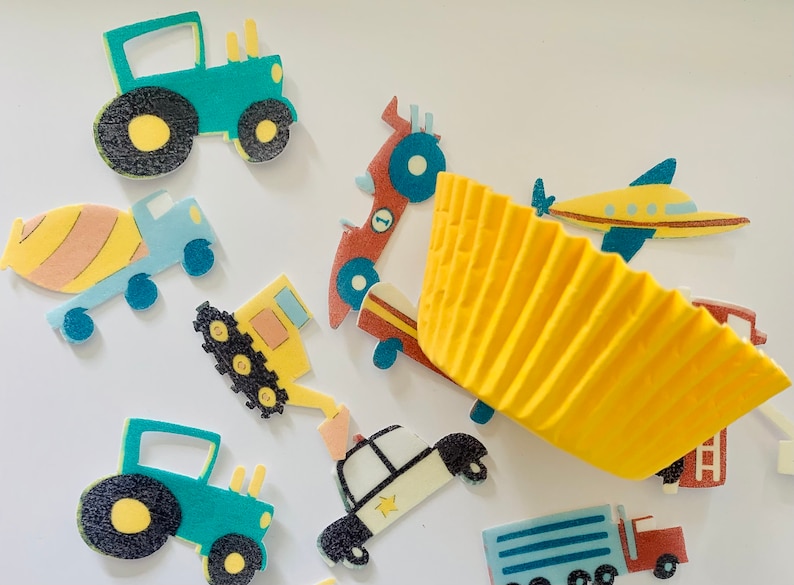 May include: Assortment of colorful vehicle-themed cupcake toppers, including a yellow construction truck, a blue and yellow airplane, a red race car, a yellow bulldozer, and two green tractors. The toppers are on a white background with a yellow cupcake liner.
