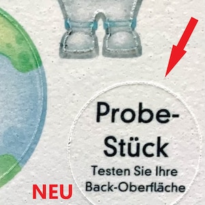 May include: A white circle sticker with black text that reads "Probe-St&uuml;ck" and "Testen Sie Ihre Back-Oberfl&auml;che". The sticker also has the word "NEU" in red text below it. The text below the sticker reads "Zu jeder Bestellung gratis!"