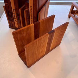 Puede incluir: Organizadores de cocina de madera en varios tamaños y diseños. Los organizadores son de madera marrón clara y oscura. Uno de ellos tiene las palabras "fruit & veg" y "bread". Otro es un pequeño estante de madera.