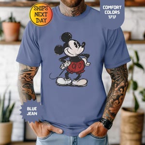 May include: Blue jean coloured t-shirt with a distressed Mickey Mouse graphic. The cartoon character is in black, white, and red. The shirt has the text "Comfort Colors 1717" and "Blue Jean".