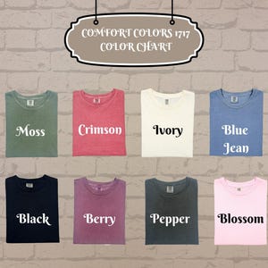 May include: A color chart displaying folded t-shirts in various colors, including moss, crimson, ivory, blue jean, black, berry, pepper, and blossom. The text "COMFORT COLORS 1717 COLOR CHART" is at the top.