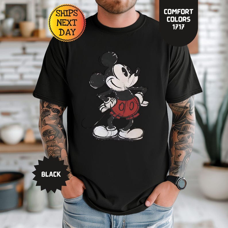 May include: Black t-shirt with a distressed Mickey Mouse graphic in black, white, and red. The shirt has the text "Comfort Colors 1717" and "Black". The cartoon character is in his classic pose.