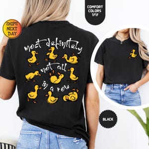 May include: Black t-shirt with a yellow duck graphic and the text "most definitely not all in a row." A small yellow duck graphic is on the front. The shirt is made of a soft, comfortable material.