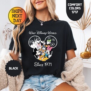 Pode incluir: T-shirt preto com um gr&aacute;fico do Walt Disney World com Mickey Mouse, Pato Donald, Minnie Mouse e Pateta. A camisa tem o texto "Since 1971". A camisa tamb&eacute;m tem o texto "Comfort Colors 1717".